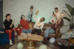 people using phones while one person is holding a cake 