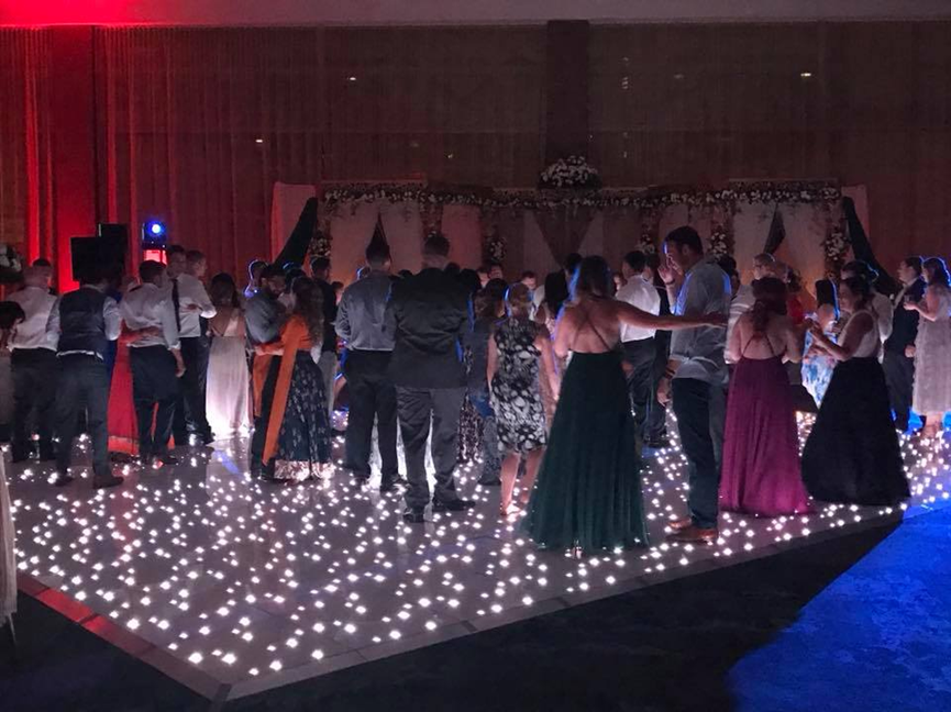 Crowd dancing on illuminated light up dance floor at an event with lighting effects